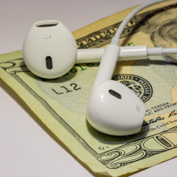 Earbuds on top of a pile of money