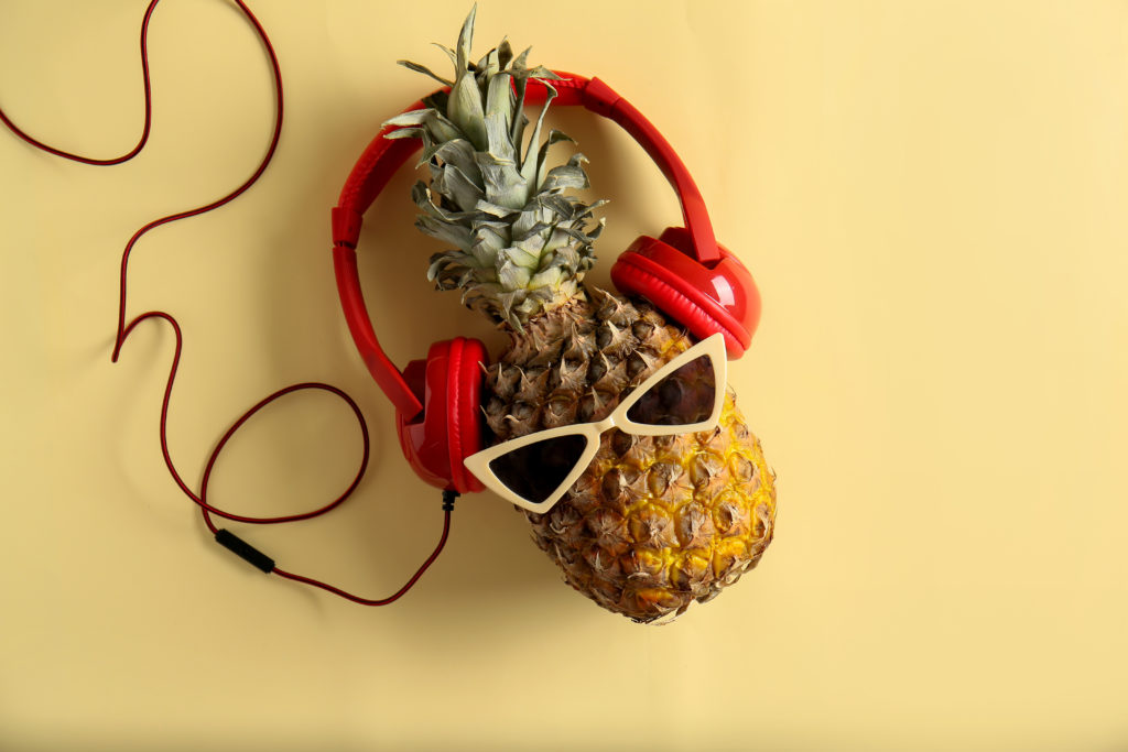 Funny pineapple with sunglasses and headphones on color background