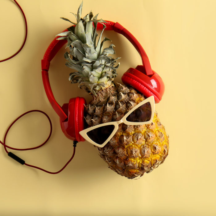 Funny pineapple with sunglasses and headphones on color background