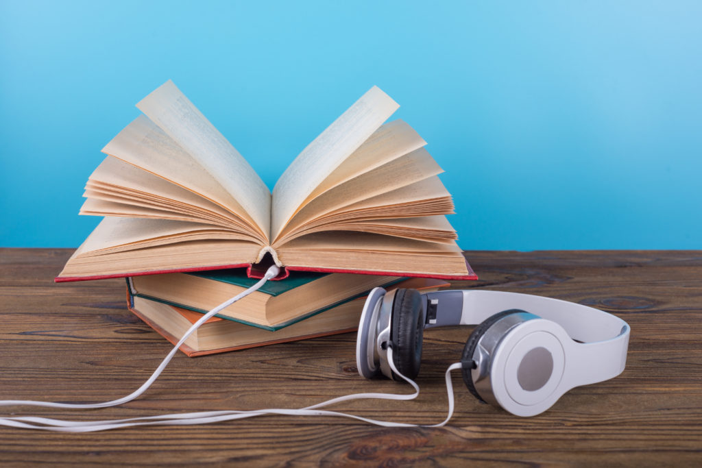 open book and connected headphones on a wooden table