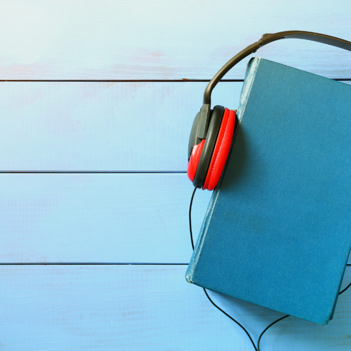 blue cover book and headphones over wooden table